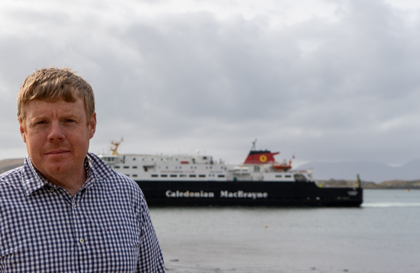 Tim stands near the water with a CalMac ferry in the background